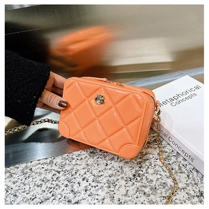 Detail of orange PVC jelly bag with quilted pattern, gold flower buckle, and chain strap