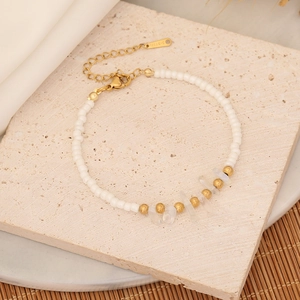 Macro view of bohemian beaded bracelet with white stones and gold accents on stone surface