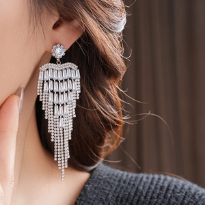 Detailed close-up of sparkling silver tassel earrings with zircon stones on a model