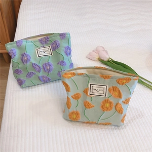 Detailed view of floral embossed makeup bags with zipper on white checkered bedding