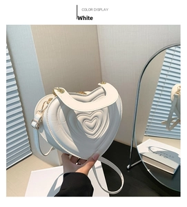Detail der weißen herzförmigen Tasche mit mehrschichtiger Prägung und Goldbeschlägen