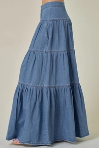 Dettaglio della gonna maxi in denim a balze blu scuro che mostra il drappeggio