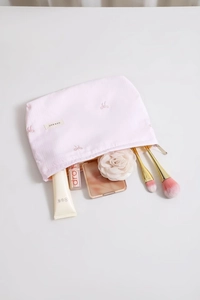 Détail de broderie nœud rose et étiquette en tissu sur trousse à maquillage rose