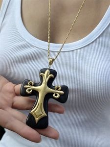 Macro detail of gothic resin cross pendant with ornate gold metal fleur-de-lis accents
