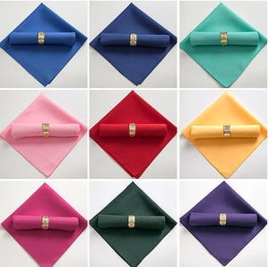 Nine colorful hotel napkins in blue, red, and green with decorative gold metal rings