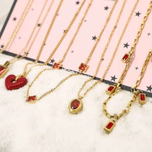 Golden necklace collection featuring red heart pendants and zircon charms on snowy background