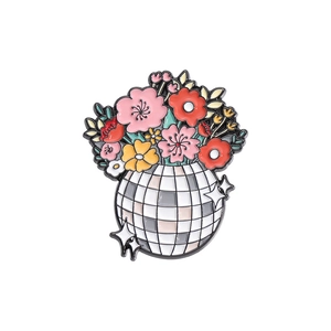 Creative enamel disco ball pin featuring colorful floral designs on a white background