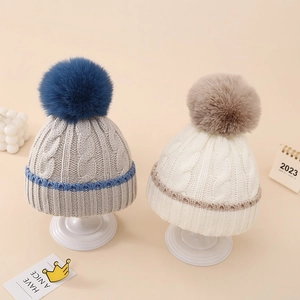 Detail of baby winter knit beanie showing twist weave texture and soft pompom detail
