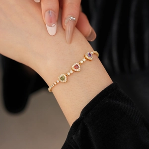 Detail of 18k gold plated bracelet with red green purple heart-shaped gemstones