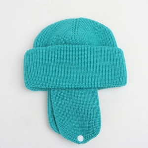 Detail of knitted winter earflap hat in teal blue with wide cuff and button closure