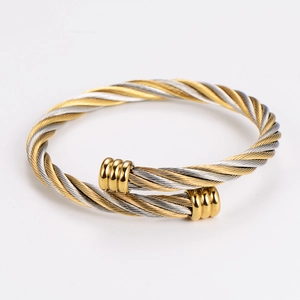 Detail of twisted cable metal cuff bracelet with gold-tone decorative end caps