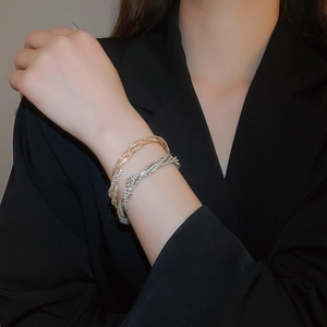 Detailed view of layered rhinestone twisted bracelets in gold and silver finish
