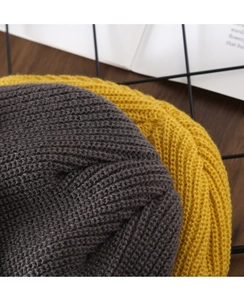 Detailed macro view showing the fine knit texture of grey and yellow winter beanies