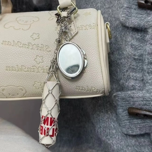 Détail du sac en cuir crème avec motif d'ours, chaîne argentée, miroir et étui à rouge à lèvres