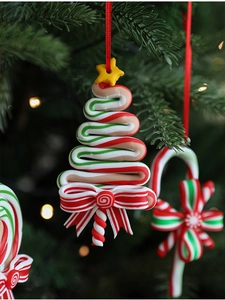 Close-up of candy cane and tree ornaments on Christmas tree with warm lights