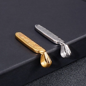 Close-up of polished gold and silver comb pendants on a black jewelry box edge