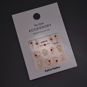 Detailed view of silver hollow heart nail stickers with red rhinestones in MJ-027 packaging
