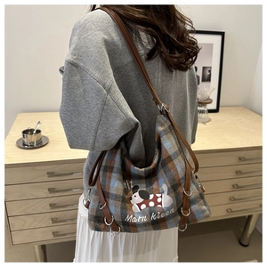Plaid canvas tote bag detail featuring cartoon dog print and leather shoulder strap