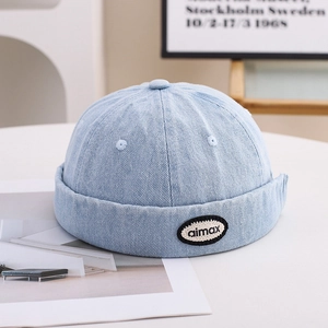 Detail of light blue denim docker hat with embroidered patch and cotton texture