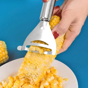 Stainless steel corn peeler tool removing kernels from a cob against a blue background