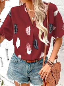 Close-up of women's burgundy short sleeve shirt featuring a vibrant feather print and lapel