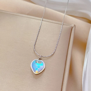 Detail of titanium steel heart pendant with iridescent finish on cream fabric