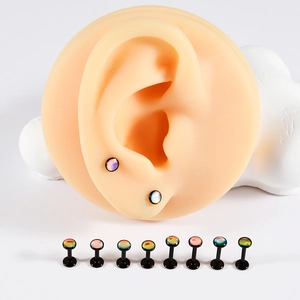 Macro detail of opal-topped black ear studs shown on a silicone ear model and in a row