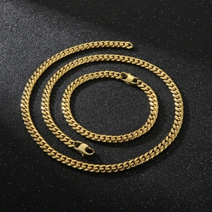 Polished gold Cuban link necklace and bracelet set displayed on a dark textured surface