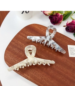 Close-up of marble pattern acetate hair claw clips on a dark wood board with roses