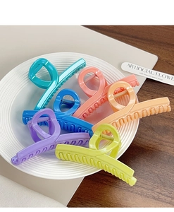 Gros plan de grandes pinces à cheveux aux couleurs bonbon dans un plat blanc