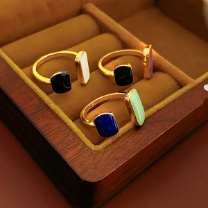 Detail view of three French geometric enamel rings displayed in a luxury wooden jewelry box