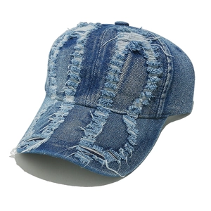 Detailed close-up of distressed denim baseball cap with heavy ripped and frayed edge effects