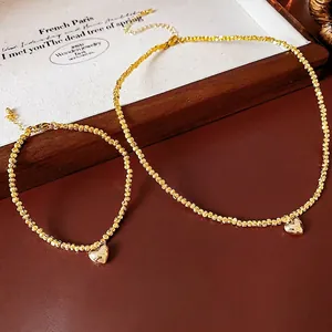 Elegant gold-tone beaded jewelry set featuring heart pendants on necklace and bracelet