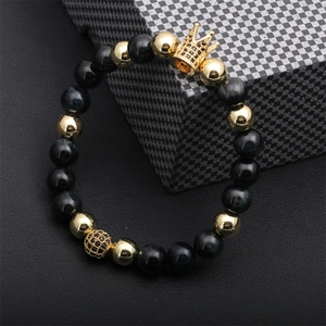 Macro shot of tiger eye beads with gold crown and micro-pave charms on a plaid box