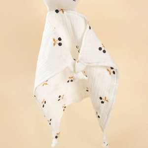 Detail of white cotton baby security blanket featuring a red cherry print and soft knotted corners