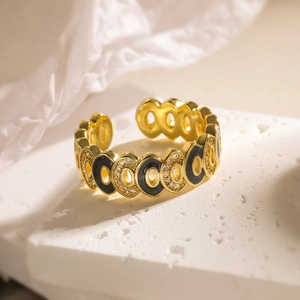 Detailed shot of bohemian gold ring with black enamel and zircons on marble base