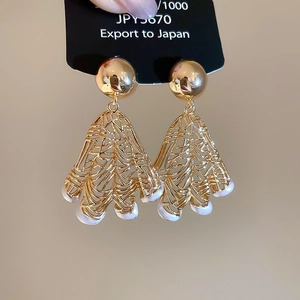 Detailed shot of golden fan-shaped hollow earrings with white semi-circular pearls
