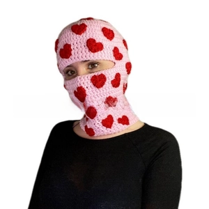 Detail of pink hand-knitted balaclava with red hearts, showing soft yarn texture and mask fit