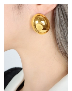Macro side view of large gold polished geometric oval stud earrings for a modern look