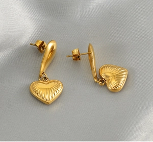 Detail of 18K gold plated heart earrings with radiant texture on silver satin background