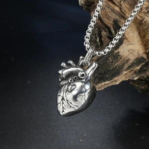 Detailed close-up of silver anatomical heart pendant with vintage metallic texture