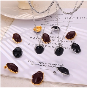 Detailed set of necklaces and earrings with enamel oval pendants on textured paper