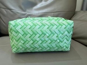 Detail of green handwoven tote bag with intricate twill texture on a leather sofa