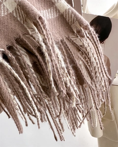 Close-up of brown and white plaid knit scarf detailing soft fringe and woven texture