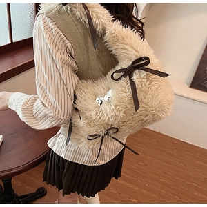Close-up of fluffy beige faux fur shoulder bag with brown leather bow and metal detail