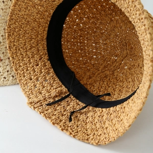 Detail view of woven straw hat interior featuring black sweatband and adjustable drawstring