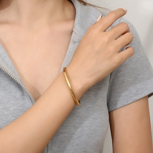 Polished minimalist gold titanium steel round bangle for women on a model's wrist