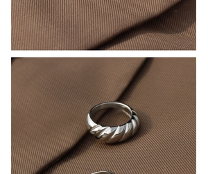 Macro view of silver croissant ring with polished twisted rope texture on fabric