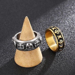Punk style skull rings in silver and gold-black finishes on a rustic display stand