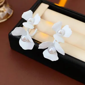 Elegant C-shaped white floral earrings with center pearls displayed on black jewelry box